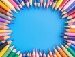© marimalina - Colorful collection of sharpened pencils arranged in a circular pattern on a bright blue background, creating an artistic frame