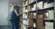 © Framestock - Multiethnic Warehouse Workers Using Tablet Computer, Having Discussion, Scanning Cardboard Boxes with E-Commerce Goods on Shelves with Scanner, Checking Inventory. Sorting Center of Delivery Service.
