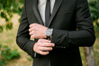 © Vasil - A man in a suit and tie is wearing a watch and adjusting his jacket. Concept of formality and attention to detail, as the man takes care to ensure his appearance is polished and professional