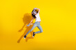 © deagreez - Young girl in casual outfit jumping with cat mask against yellow backdrop, embodying playful and imaginative cosplay