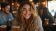 © Prostock-studio - A young woman with wavy hair smiles brightly while holding a drink in a warm and inviting bar. Friends are seen chatting in the background, enjoying their time together.