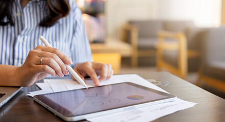 close up executive businesswoman hand using stylus pen to pointing on tablet screen to show company profit monthly in the meeting event at conference room , business strategy concept