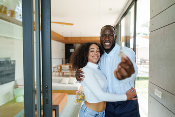 diverse couple in casual attire celebrates milestone moment displaying house keys at their newly pur