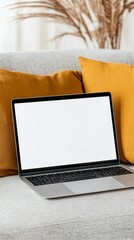 Wall Mural - modern laptop with blank white screen placed on comfortable sofa with soft pillows in cozy living ro