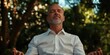 © gunzexx png and bg - A calm middle-aged man sits peacefully with closed eyes in a lush green environment, embodying tranquility and mindfulness amid nature's soothing backdrop.