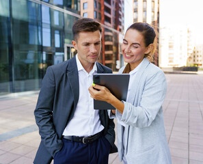 Professionals discussing work on a tablet in a modern urban setting during daylight hours