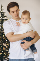 Father holding his baby son near Christmas tree