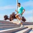 © muse studio - Man exercises by running down outdoor stairs on a sunny day in an urban park setting