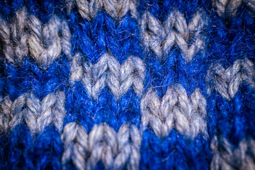 A detailed macro shot of blue and white knitted fabric, showcasing the soft texture and intricate weave of the yarn. The color contrast highlights the artistic pattern.