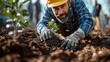 © Solikah - A man plants a young tree in rich soil, promoting environmental care.