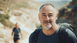 © NNS Studio - Portrait active middle-aged man forties hiking scenic mountain landscape exuding confidence fitness passion outdoors natural sunlight terrain vibrant habit fresh casual advertising promotion sky