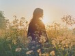 © Atmospheric stock - Silhouette of young caucasian female in sunlit wildflower field at sunset