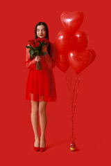 Wall Mural - Beautiful young woman with kiss marks on her face holding bouquet of roses and heart shaped air balloons on red background