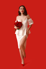 Wall Mural - Young woman with bouquet of beautiful roses on red background