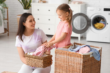 Wall Mural - Young mother, her daughter and basket with laundry at home