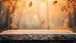 © BerkahStock - Wooden table with autumn leaves falling.