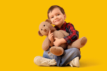 Canvas Print - Cute little boy hugging toy bear on yellow background