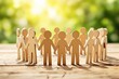 © Pixels Hunter - Wooden figures of people holding hands in a circle on a wooden surface with a bright green blurred background.