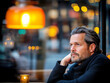© Vasili - A thoughtful man sits at a warmly lit cafe table, lost in deep contemplation. The urban ambiance exudes quiet introspection and a reflective mood.