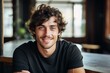 © nsit0108 - Happy young man with curly hair smiling in cafe, enjoying relaxed atmosphere
