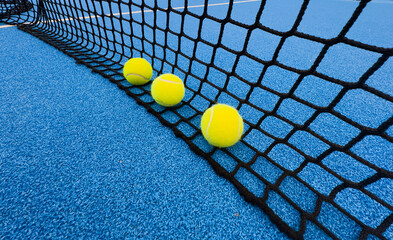 Wall Mural - Yellow ball on floor behind paddle net in blue court outdoors. Padel tennis is a racquet game. Professional sport concept