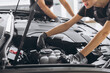 © anatoliycherkas - Trying to identify the source of the problem. Close-up shot of two mechanics man and woman working together at open hood on a car in an auto repair shop.