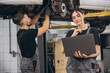 © anatoliycherkas - Young expert female inspects repair checklist with automotive mechanic worker partner, quality suspension technician team at fix garage. Vehicle maintenance service works industry occupation job.