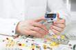 © vizafoto - A young doctor in a white coat holds a device for measuring blood saturation. Close-up.