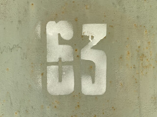 White number 63 on textured old background. Sixty-three