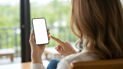 Back view of a woman using a smartphone with a blank screen, ideal for app design presentations, products or website mockups in a bright and natural setting