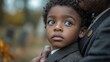 © Kaizenart - Close-up portrait of a young boy embraced by a man outdoors.
