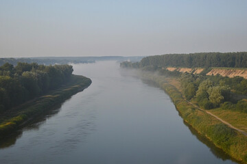 Wall Mural - Morning fog blankets serene river landscape