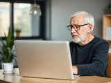 Happy eldery man with laptop in apartment interior.