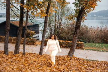 Wall Mural - Young hispanic female enjoying autumn in a forest near a lake