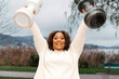© Ktn - Joyful african female adult lifting dumbbells outdoors near lake