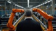 © Vadym - Man observes car assembly line with robots. Modern auto manufacturing. Robots assemble cars on conveyor belt. Worker watches process. Advanced tech in auto industry. Efficient production. India.