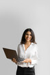 © Stock 4 You - Vertical portrait of young middle eastern Israel businesswoman using laptop pc online application for work isolated on white wall. Smiling happy indian, arabic woman in business suit holding computer