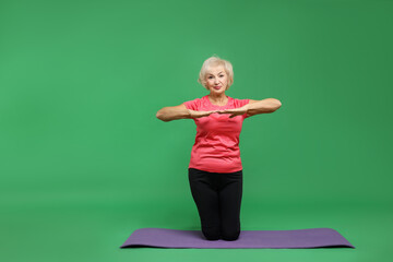 Sticker - Senior woman exercising with fitness mat on green background