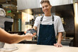 © New Africa - Cafe worker taking payment from client via terminal indoors
