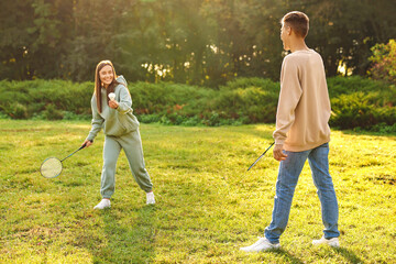 Young woman and man playing badminton in park on sunny day, selective focus