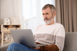© New Africa - Mature man with laptop on sofa at home