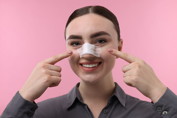 Wall Mural - Woman with medical bandage on her nose after plastic surgery operation against pink background