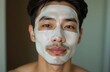 © Olga - Portrait of a young Asian man with a cosmetic mask on his face at home. Facial skin care