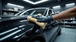 © anko - Professionelle Autoaufbereitung in einem Fachbetrieb: Nahaufnahme der Reinigung und Lackaufbereitung  von einem Auto mit glänzender, schwarzer Lackierung