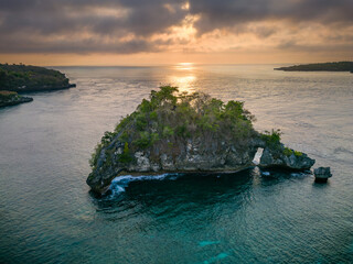 Canvas Print - Drone shot of a small tropical rock and warm ocean at sunset (Nusa Penida, Bali)