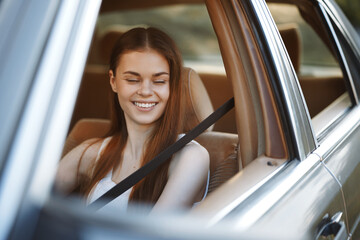 Poster - Happy young woman enjoying a road trip in a car, smiling with eyes closed, wearing a casual outfit, emphasizing joy and freedom.