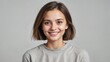 © Lexi - Close-up portrait of a young woman with a short hairstyle smiling warmly in a gray shirt against a light background