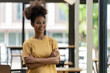 © Songsak C - A successful young African-American female entrepreneur, small business owner, female office employee, and black businesswoman wearing a casual shirt stands confidently with arms crossed.