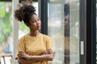 © Songsak C - A successful young African-American female entrepreneur, small business owner, female office employee, and black businesswoman wearing a casual shirt stands confidently with arms crossed.