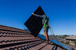 © Austockphoto - Electrician positioning bifacial solar panels on roof for solar system install on residential home